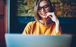 Eine Frau schaut glücklich auf ihren Laptop-Bildschirm.